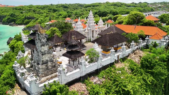 Cinematic aerial pull away from Pura Geger Dalem Pemutih temple on a cliff, revealing Bali coastline, Indonesia