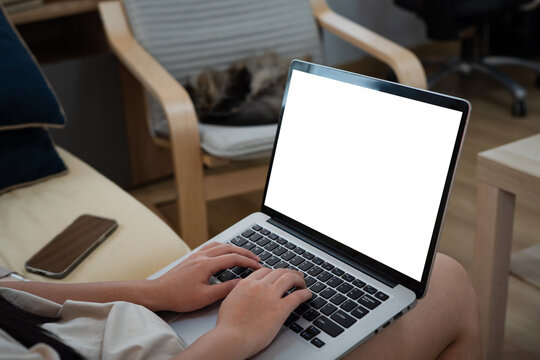 Young woman using laptop computer at home. Blank empty white screen mock up. Freelance, student lifestyle, education, web conference, video call, technology and online shopping concept