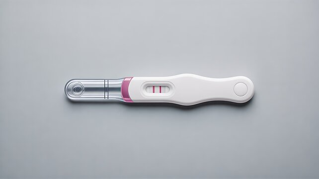 Positive pregnancy test device showing two lines on minimal gray background close up concept of fertility and early pregnancy detection
