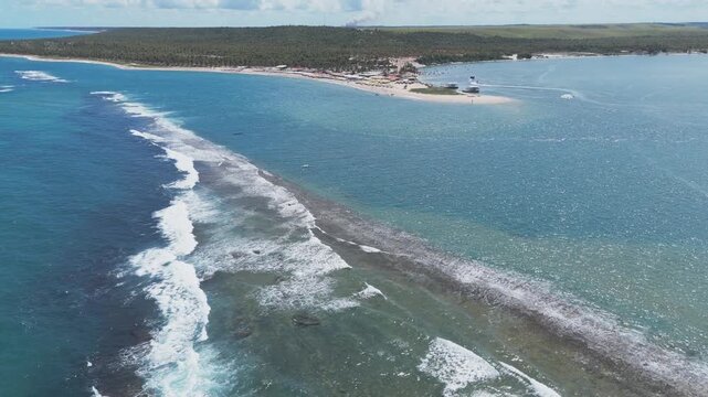 Aerial drone video of a beach in Brazil, Alagoas state, in Gunga beach, near Maceio, large barrier of stones and corals near the paradisiacal beach full of palm trees.