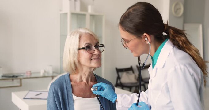 Cardiologist doctor holding stethoscope to listening of middle age woman heartbeat and lungs sounds. Cardiovascular disease preventive care, regular heart health checkup for adult patients, cardiology