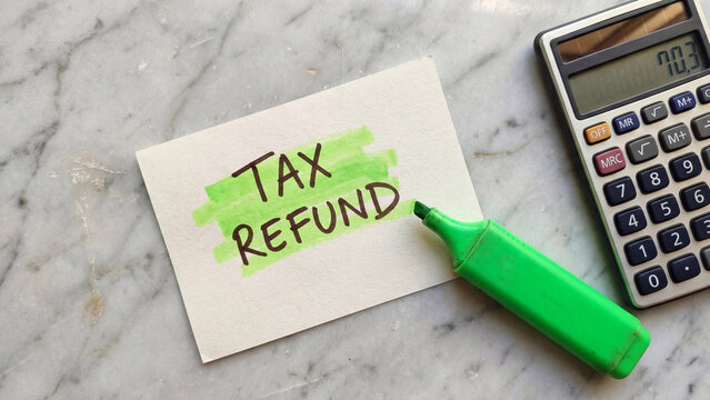 Tax refund financial return concept highlighted notecard with green marker and calculator for personal income tax overpayment reimbursement filing benefit and fiscal year planning