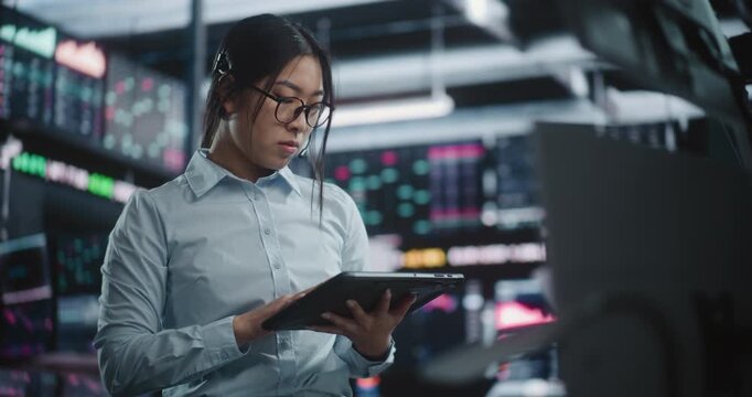 Focused Woman Cross Referencing Real Time Financial Charts on Digital Tablet While Discussing Market Moves in Professional Headset. Concept of High Level Multitasking and Expert Data Verification.