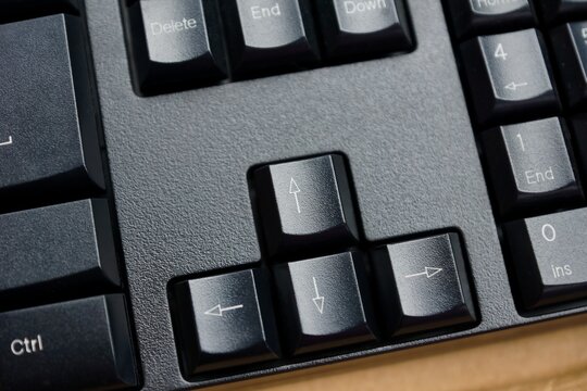 Close-up of arrow keys on a black computer keyboard showing directional navigation buttons used for cursor movement and interface control in modern digital devices.