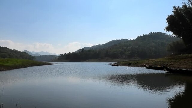 The serene and beautiful landscape with the Periyar River at Ayyappankovil in Idukki, Kerala, India | Wooden boats are parked on the riverbank