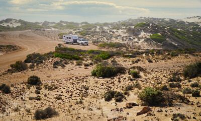 Naklejka premium Four-Wheel drive and caravan parked on sandy coastal dunes in South Australia during a road trip