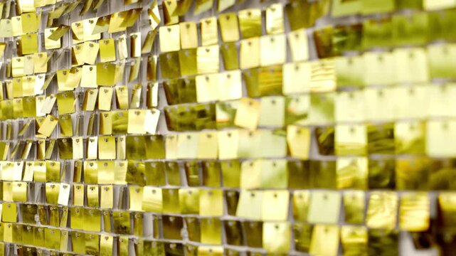 Slow motion panning tracking shot of gold sequin curtain rippling and reflecting light on event stage interior backdrop