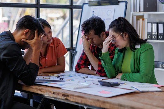 A team of four individuals resolves issues together, shaking hands in agreement, emphasizing collaboration and teamwork in a professional setting amidst challenges.