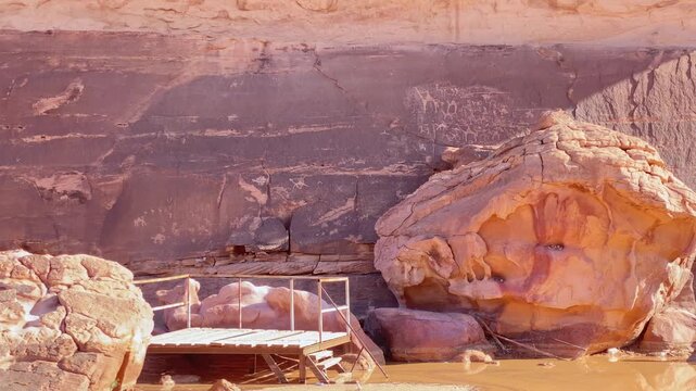 Ancient petroglyphs and inscriptions carved into sandstone rock wall in Wadi rum with viewing platform archaeological heritage Jordan