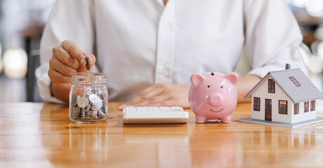 While focusing on financial strategy, an individual transfers coins from a savings jar to a pink...