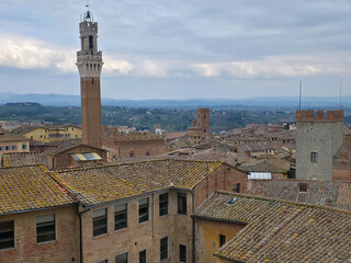 Obraz premium Panoramic view of Siena city center with Torre del Mangia tower, historic rooftops and the rolling hills of Tuscany in the background, Italy