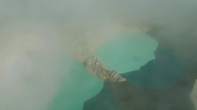 Drone aerial reveal of Mount Kelimutu tri-colored crater lakes on Flores Island, Indonesia, vibrant volcanic lakes changing hues amid dramatic mountain landscape, cinematic nature shot.