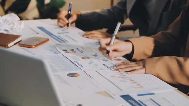 Accountant reviewing printed financial reports at messy office desk with calculator and sticky notes under soft window daylight for audit and corporate finance work