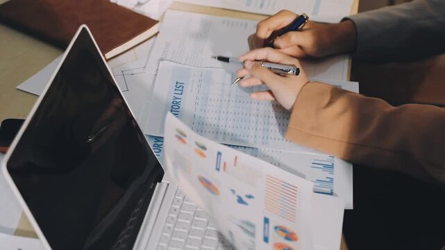 Accountant reviewing printed financial reports at messy office desk with calculator and sticky notes under soft window daylight for audit and corporate finance work