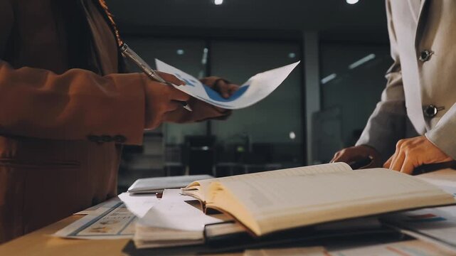 Accountant reviewing printed financial reports at messy office desk with calculator and sticky notes under soft window daylight for audit and corporate finance work
