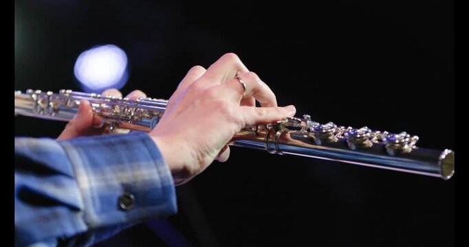 A slow motion video of the hands of a flute playing playing the flute during a solo performance
