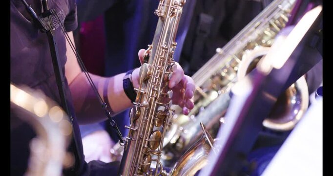 A slow motion video of a saxophone player playing their instrument during an wind ensemble rehearsal before a live performance