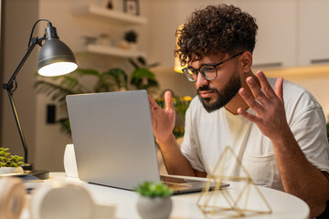 Arabian man at home opens laptop reads fail notice for tender feels upset stressed. Egyptian guy...