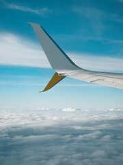 Obraz premium Airplane wing above clouds during flight with blue sky aerial travel perspective