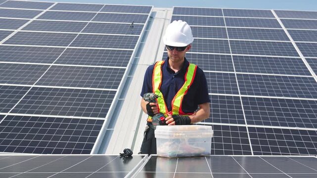Technician installing solar panels on factory roof for green energy. A skilled technician in safety gear is working on a solar panel installation on rooftop. clean energy renewable power technology.