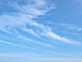 Obraz premium Wispy cirrus clouds on a bright blue sky background. Perfect for nature backgrounds, weather-related themes, and tranquil atmosphere designs