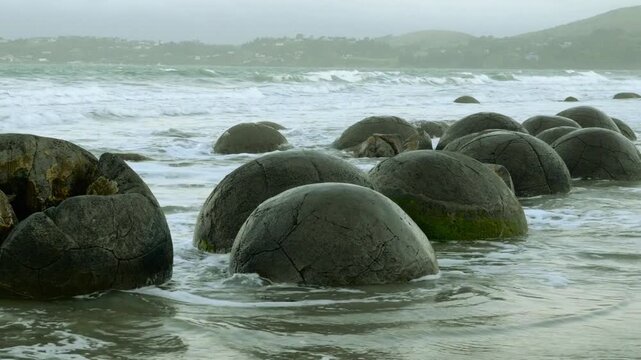 Drone aerial of Moeraki Boulders on Koekohe Beach, South Island, New Zealand, massive spherical stones scattered along the coast, ancient geological wonder filmed March 22, 2025.