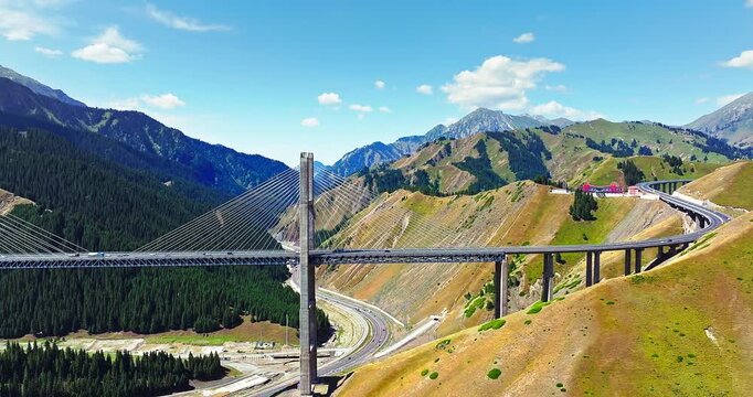 Aerial view of Guozigou cable-stayed bridge spanning a green mountain valley in Xinjiang, China.
