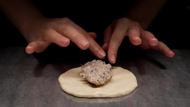 Closeup sequence of raw dough being prepared with a savory meat filling on a dark counter surface, highlighting texture, culinary technique, and cooking preparation