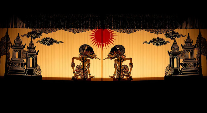 Javanese shadow puppets silhouette against glowing orange sun