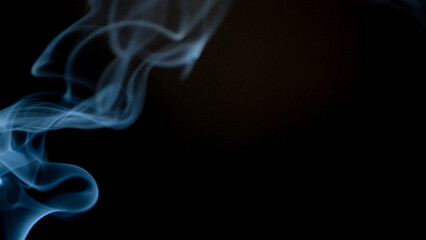 An artistic image showing wisps of smoke dancing against a dark background, creating an atmosphere of mystery and intrigue. The smoke swirls and curves, adding a dynamic and ethereal touch