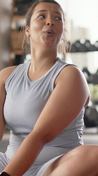 Vertical video: Laughing woman in lilac top reaching high-five after partner's joke in gym, mat