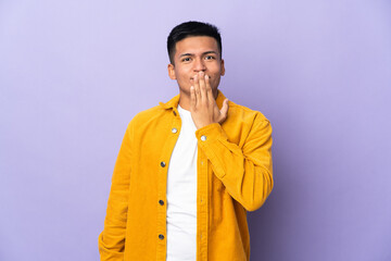 Fototapeta premium Young Ecuadorian man isolated on purple background covering mouth with hand