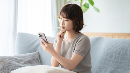 スマートフォンを見ながら考える女性, Woman thinking while looking at a smartphone © Trickster*