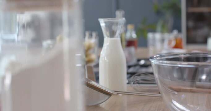 Camera pulling back while racking focus, milk carafe centering and whisk moving forward for baking