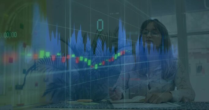 Chart animation shifting, woman at desk glancing up and writing in notebook tracking market trends