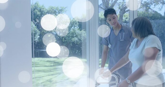 Moving nurse in scrubs, steth guiding walker user at glass doors for company, bokeh, copy space