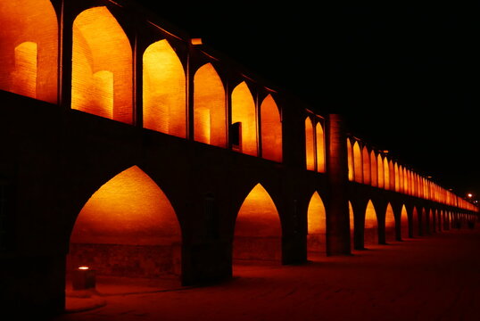 Golden night illumination of the historic Si o se pol bridge featuring iconic arches and Safavid architecture in Isfahan Iran