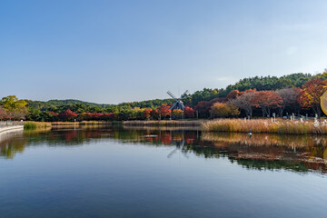 Obraz premium Autumn landscape of Ulsan Grand Park with a windmill and lake reflection, South Korea
