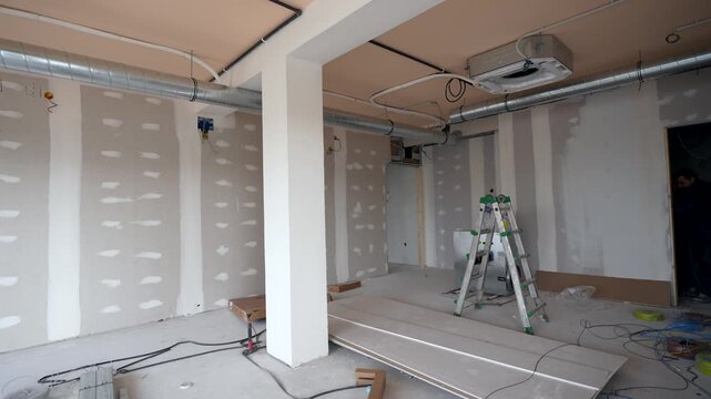 Professional hvac technician installing a modern air conditioning and ventilation system with pipes on the ceiling of a room during a commercial building renovation and construction process