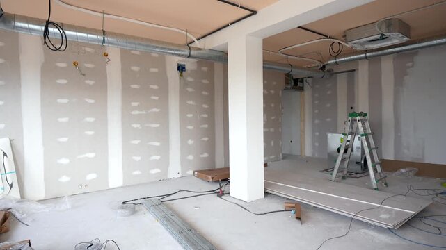 Interior of a commercial space during renovation with newly installed drywall, electrical wiring, and a prominent hvac ventilation system being fitted, showing the progress of modern construction