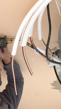 Professional hvac technician brazing copper pipes with a gas torch during the installation of a new air conditioning system, connecting the refrigerant lines for home climate control