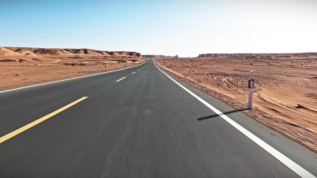 Long straight asphalt highway stretching through vast arid desert landscape in Xinjiang, China.