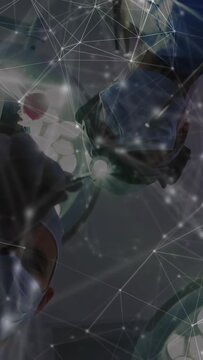 Vertical video: Surgeon adjusting team manipulating tools under lights data overlay guiding surgery