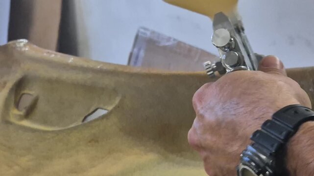 Spraying glue headliner, person applies adhesive to car ceiling panel for automotive interior restoration