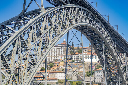 Detalle de la arquitectura de hierro del ic&oacute;nico puente sobre el r&iacute;o Duero, con vista a los edificios tradicionales y tejados del casco hist&oacute;rico de Oporto.