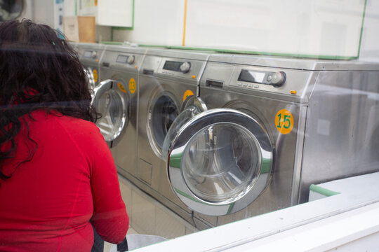 Femme en attente du lavage de linge dans une laverie