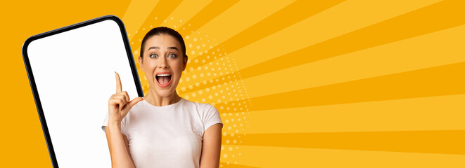 A person stands with a mobile device in hand, pointing at the screen with excitement. The background is bright and colorful with rays and patterns creating a lively collage effect. © Prostock-studio