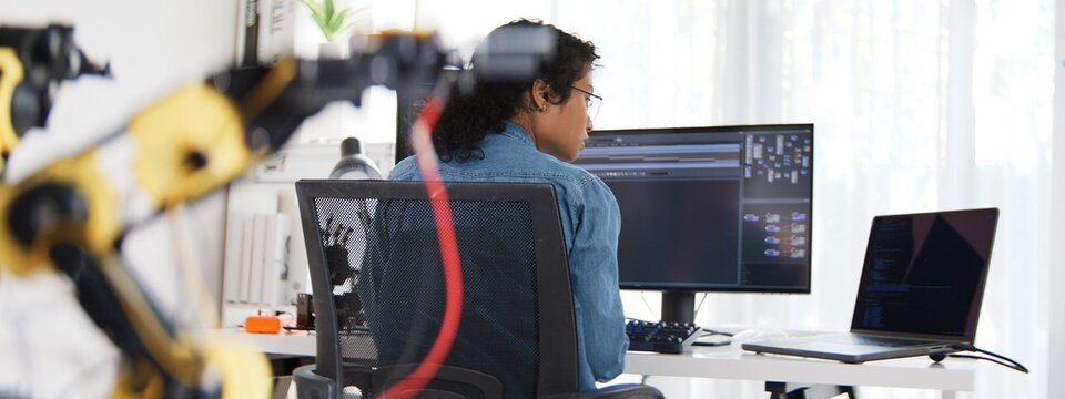 South east asian female engineer developer use laptop computer work at home office with robotic arms. Science and technology, Robot automated innovation, Electrical engineering manufacturing concept.
