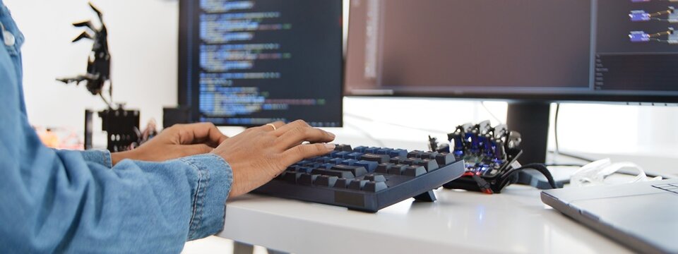 Close up of female engineer developer type on computer keyboard at home office with robotic arms. Science and technology, Robot automated innovation, Electrical engineering manufacturing concept.