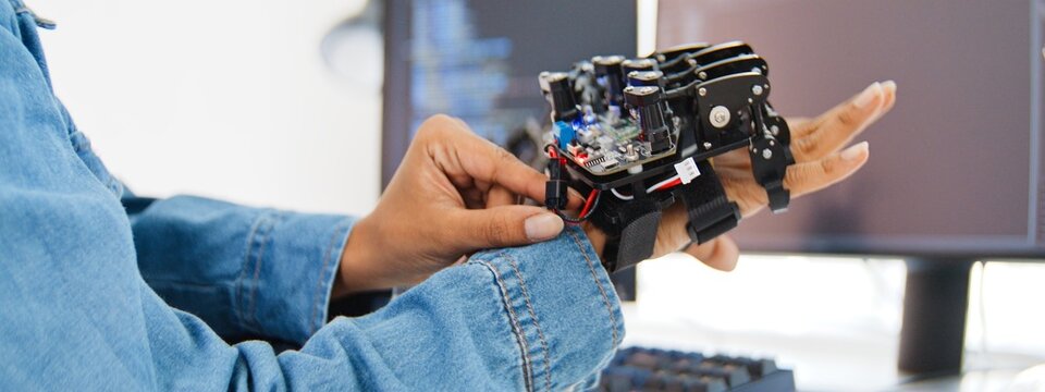 Close up of female engineer developer examine robotic arm with laptop computer at home office. Science and technology, Robot automated innovation, Electrical engineering manufacturing concept.